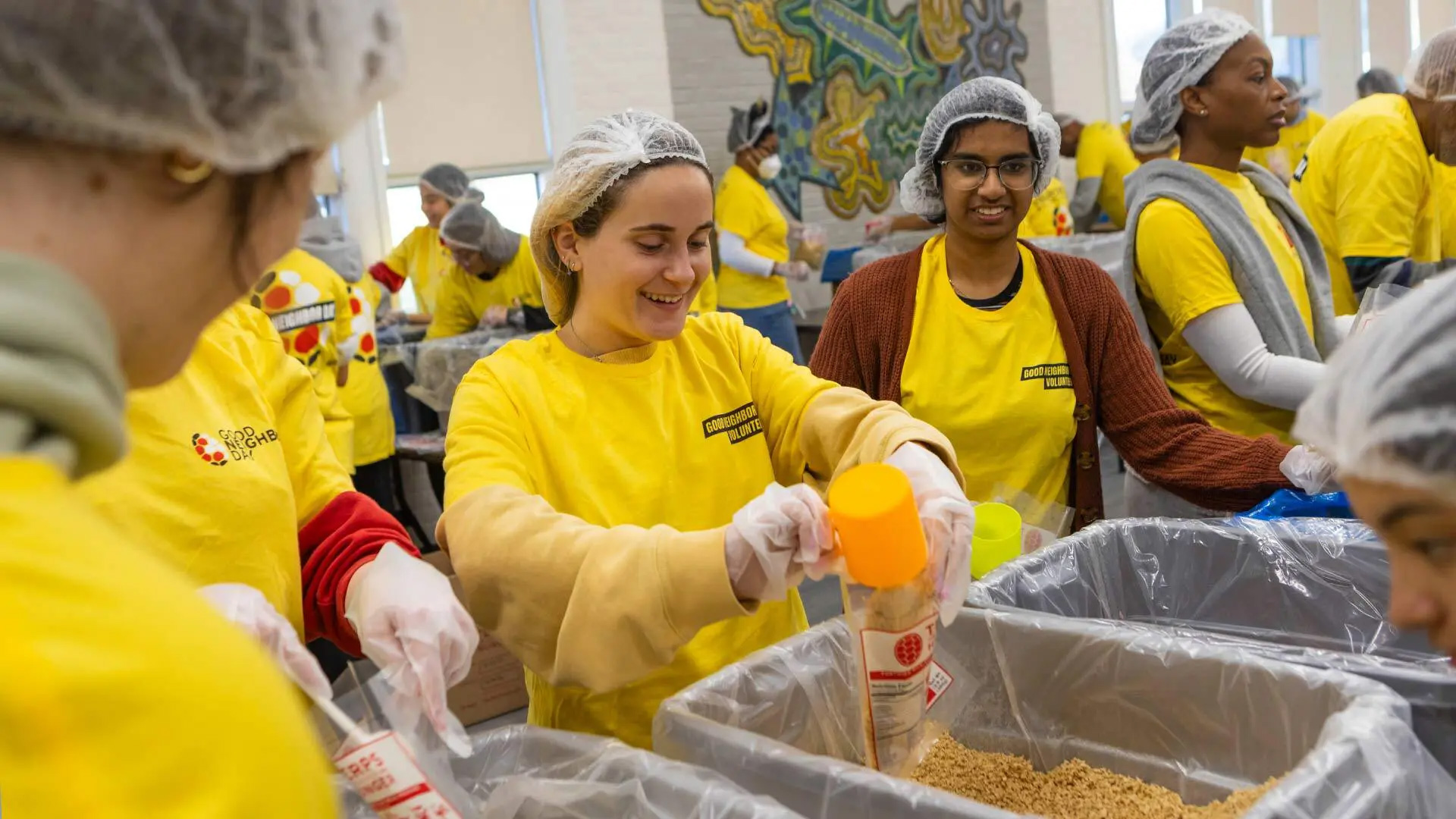 Maria Klevorn ’26 (center) and Nikki Sur ’26 (right of center) assemble meal kits at the Terps Against Hunger event at the Langley Park Community Center on Good Neighbor Day on Saturday. Volunteers there packed 27,216 wholesome meals for local families.